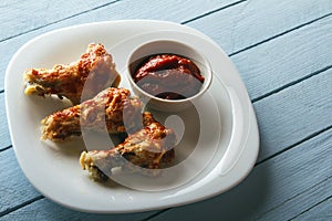 Crispy chicken wings. Freshly cooked dish on a white plate on a wooden table. View from above with copy space