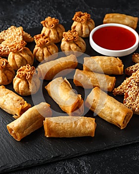 Crispy Chicken wontons, vegetable spring rolls and prawn toasts with sweet chilli sauce. chinese selection. fast food.