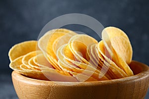 Crispy chips in a wooden bowl on a gray dark table. Snack.