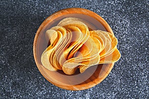 Crispy chips in a wooden bowl on a gray dark table. Snack.