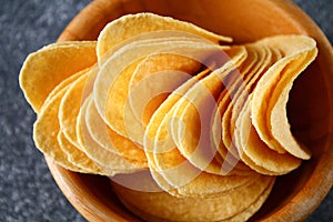 Crispy chips in a wooden bowl on a gray dark table. Snack.