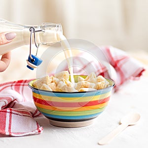 Crispy corn pads in a clay bowl with a bottle of fresh milk on a light background. Healthy breakfast cereals. Amaranth