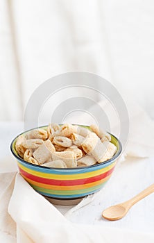 Crispy corn pads in a clay bowl with a bottle of fresh milk on a light background. Healthy breakfast cereals. Amaranth