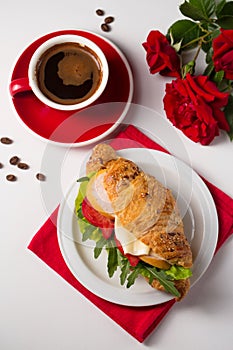 Crispy croissant with ham, cheese and vegetables with a cup of coffee, top view