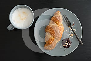 Crispy croissants with jam and smashed walnuts on a plate with fork for a breakfast. Fresh croissant as breakfast. French croissan