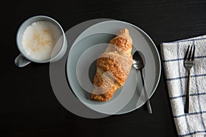 Crispy croissants with jam and smashed walnuts on a plate with fork and a cup of coffee for a breakfast. Fresh croissant as breakf