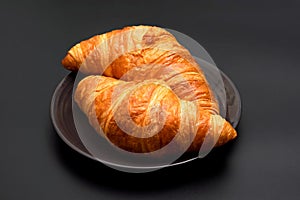 Crispy delicious croissants on a black background. Homemade baking