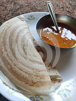 2 crispy double yummy hot tastey dosa with hot sambhar in white plate and silver utensils and spoon