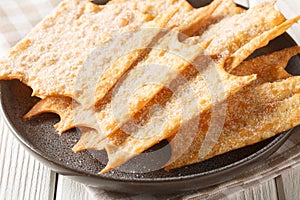 Crispy French holiday fritters Oreillette close-up in a plate. horizontal