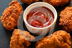 Crispy fried breaded chicken strips with red sauce on a dark background