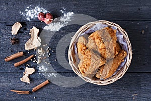 Crispy fried chicken in a basket on wooden table.Top view