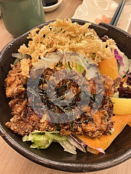 Crispy fried chicken karage salad on a black bowl