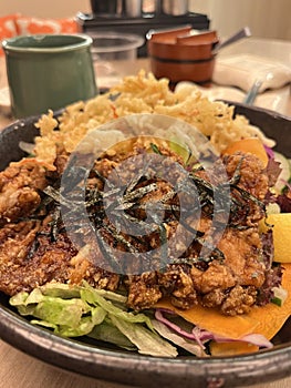 Crispy fried chicken karage salad on a black bowl