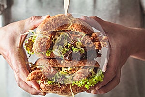 Crispy fried chicken sandwiches with coleslaw salad in man hands