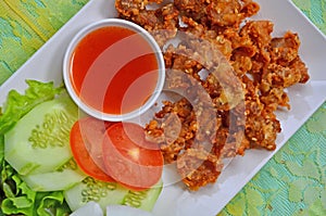 Crispy fried chicken tendons with chili sauce and vegetable in white plate