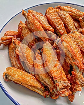 Crispy fried chicken wings served on a white plate, the seasoning seeped into the meat photo