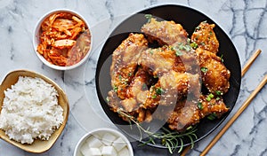 Crispy fried korean chicken wings in galbi sauce with pickled radish, kimchi, and rice side dishes photo