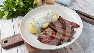 Crispy fried pork with creamy parsley sauce and boiled potato in the plate on the table or stegt flÃ¦sk