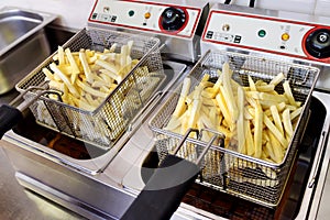 Crispy golden potato chips draining on a fryer