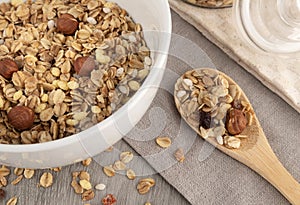 Crispy granola with nuts in bowl on light table background. Healthy cereal breakfast.