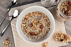 Crispy granola with nuts in bowl on light table background. Healthy cereal breakfast.