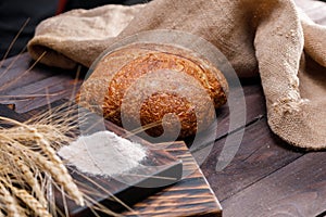 Crispy hand-made loaf of whole-grain rustic bread on a board covered with flour. Rustic