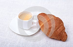 Crispy homemade fresh croissants and cup of coffee espresso on a white background, morning breakfast, selective focus