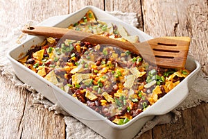 Crispy homemade frito pie with beef, cheese, corn, beans and chips close-up in a baking dish. horizontal