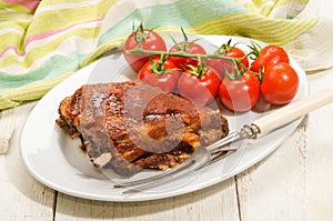 Crispy marinated ribs and fresh tomatoes on an oval plate