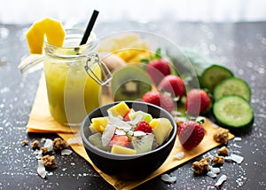 Crispy muesli with fresh strawberries, kiwi, mango and coconut flakes with delicious green smoothie in a jar