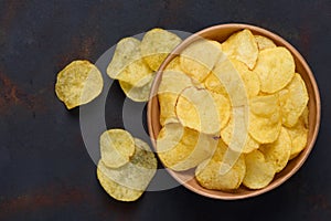 Crispy potato chips in bowl on dark table