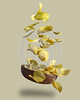 Crispy potato chips falling into clay piala, close-up, isolated background