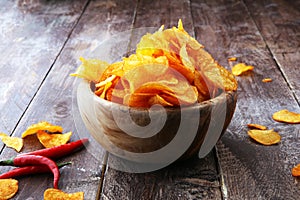 Crispy potato chips. Paprika chips on brown wooden background