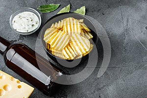 Crispy potato chips. Slices of potato, roasted with sea salt  with Cheese and Onion, with dipping sauces , and bottle of beer , on