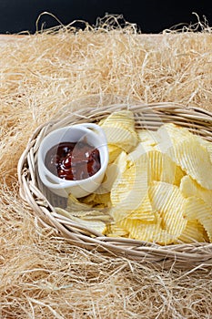 Crispy potato chips in a wicker bowl with ketchup.