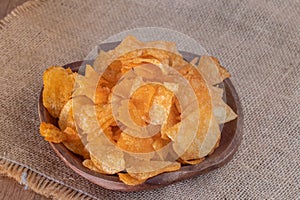 Crispy potato chips on wooden bowl