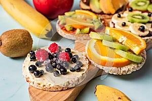 Crispy puffed rice cakes on table with fresh fruit kiwi banana apple blueberries raspberries and orange on the table - close up