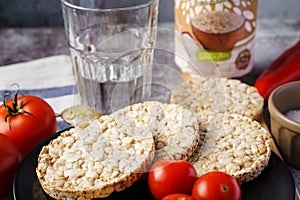 Crispy puffed rice cakes on table hummus spread and tomato vegetables and sesame seeds on the table - close up view on healthy