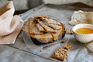 Crispy rectangular crispbreads with sesame seeds and seeds with natural honey in an interestingly decorated composition with wood