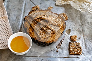 Crispy rectangular crispbreads with sesame seeds and seeds with natural honey in an interestingly decorated composition with wood