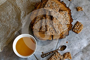 Crispy rectangular crispbreads with sesame seeds and seeds with natural honey in an interestingly decorated composition with wood