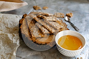 Crispy rectangular crispbreads with sesame seeds and seeds with natural honey in an interestingly decorated composition with wood