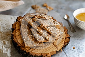 Crispy rectangular crispbreads with sesame seeds and seeds with natural honey in an interestingly decorated composition with wood