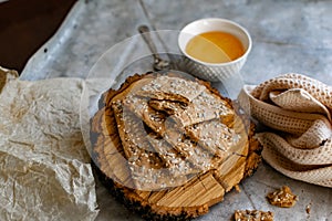 Crispy rectangular crispbreads with sesame seeds and seeds with natural honey in an interestingly decorated composition with wood