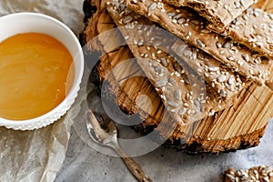 Crispy rectangular crispbreads with sesame seeds and seeds with natural honey in an interestingly decorated composition with wood