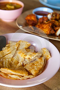 Crispy roti on a plate set on a wood table.