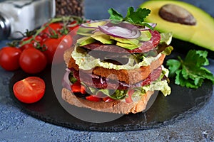 Crispy sandwich with salami, salad and vegetables on the kitchen table.