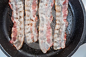 Crispy smokey fried bacon slice or strip. Unhealthy fat food, fattenig ingredient. Red Thin slice or strip or rashers of bacon is