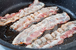 Crispy smokey fried bacon slice or strip. Unhealthy fat food, fattenig ingredient. Red Thin slice or strip or rashers of bacon is