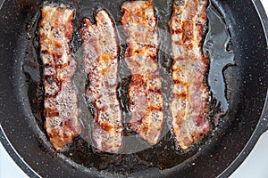 Crispy smokey fried bacon slice or strip. Unhealthy fat food, fattenig ingredient. Red Thin slice or strip or rashers of bacon is